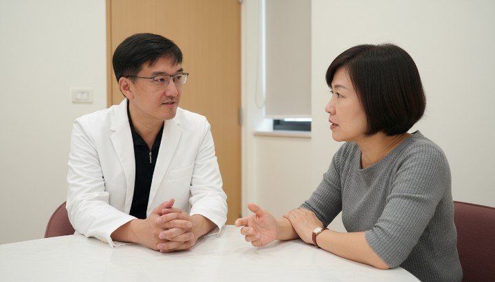 醫師說明如何進行自律神經平衡自我檢測 透過量表進行身心壓力狀態的自我檢測 民眾閱讀診所手冊進行症狀的自我檢測